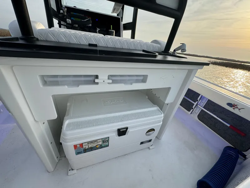 Slide: The Image of 2025 Crevalle 24 HCO boat interior with cooler and seating, sunset view. - 42