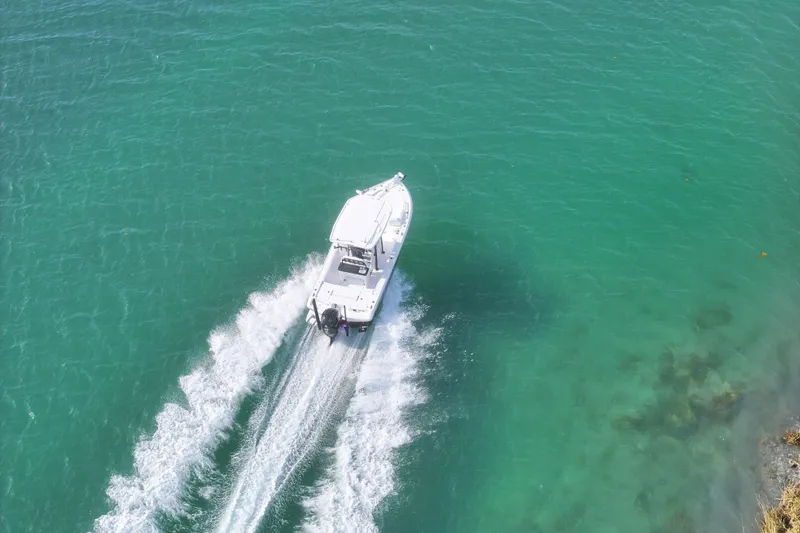 Slide: The Image of Aerial view of 2025 Crevalle 24 HCO boat cruising on clear turquoise water. - 5