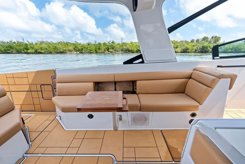 Slide: The Image of 2022 Aviara AV40 OB boat interior with tan seating and wooden table, scenic water view. - 30