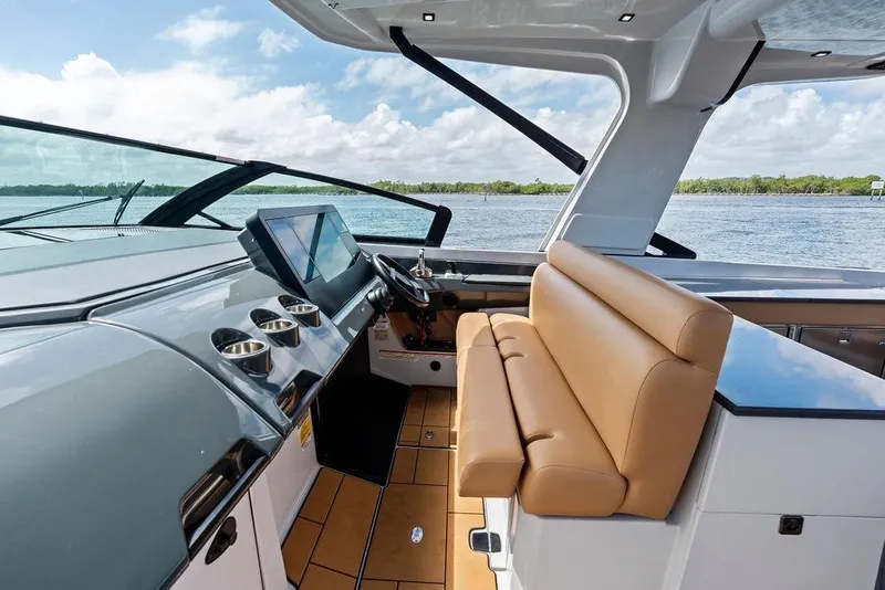 Slide: The Image of 2022 Aviara AV40 OB boat interior with modern dashboard and tan seating, overlooking water. - 40