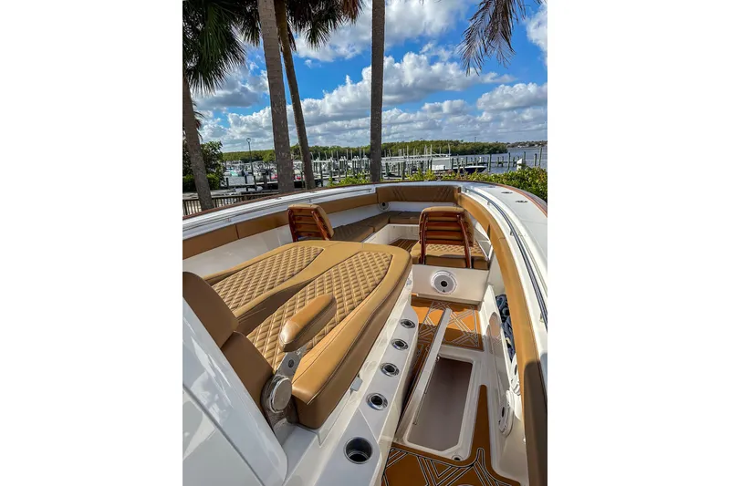 Slide: The Image of 2022 Invincible 39 Open Fisherman boat interior with tan seating and scenic marina view. - 10