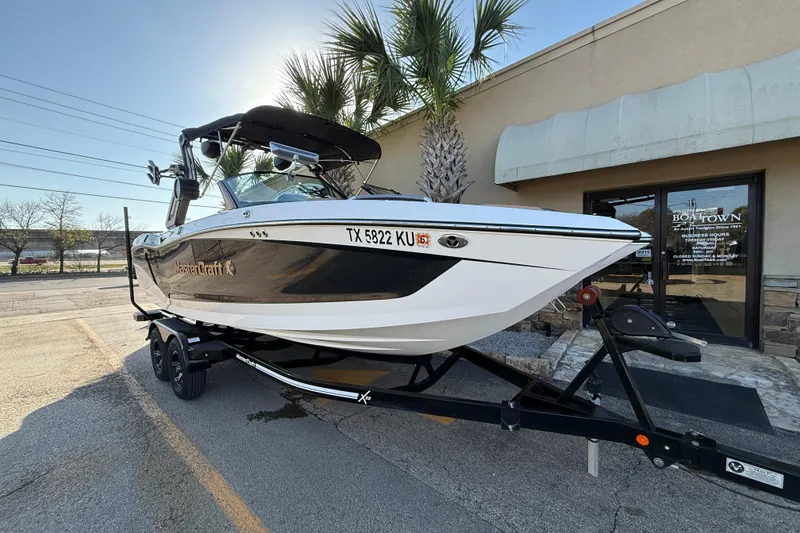 Slide: The Image of 2023 MasterCraft X22 boat on trailer, parked outside a building. - 1