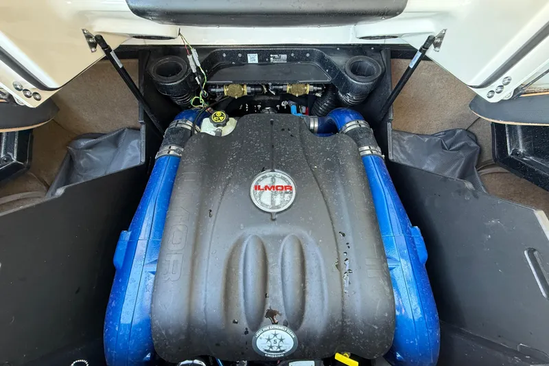 Slide: The Image of 2023 MasterCraft X22 engine compartment with Ilmor engine, featuring blue hoses and black cover. - 16