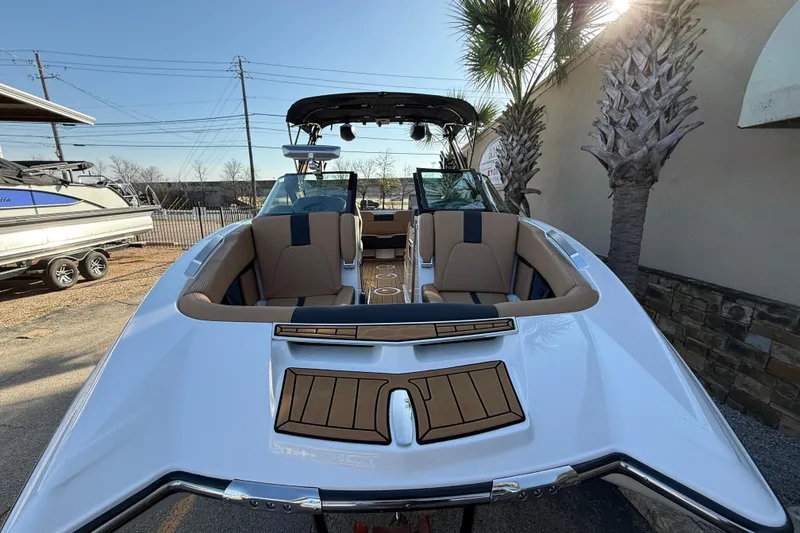 Slide: The Image of 2023 MasterCraft X22 boat with sleek design and luxurious seating, parked outdoors. - 2