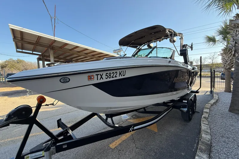Slide: The Image of 2023 MasterCraft X22 boat on trailer, parked outdoors under clear sky. - 3