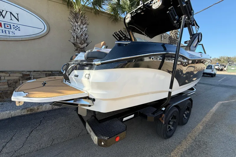Slide: The Image of 2023 MasterCraft X22 boat on trailer, parked outdoors near palm trees. - 5