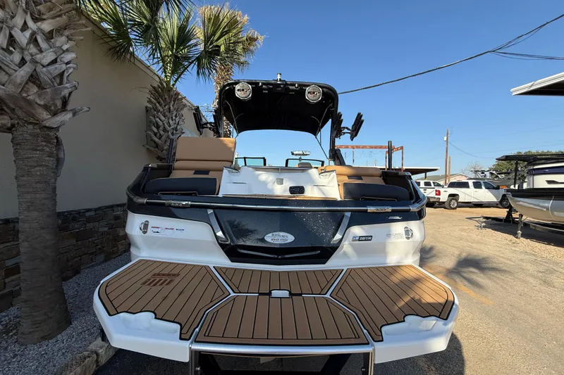 Slide: The Image of 2023 MasterCraft X22 boat with teak deck, parked outdoors under clear blue sky. - 6