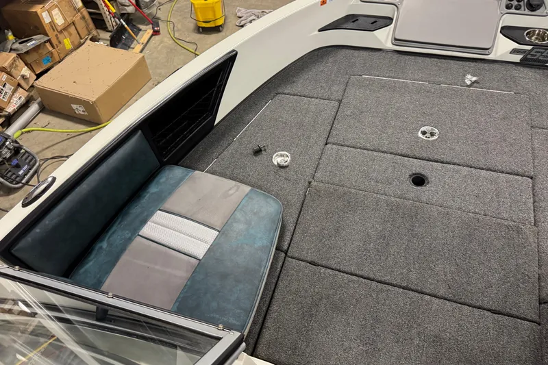 Slide: The Image of 2023 Ranger 1850MS boat interior with gray carpet and seating, in a workshop setting. - 19