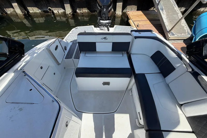 Slide: The Image of 2022 Monterey M-65 boat interior with white and black seating, docked by the water. - 11