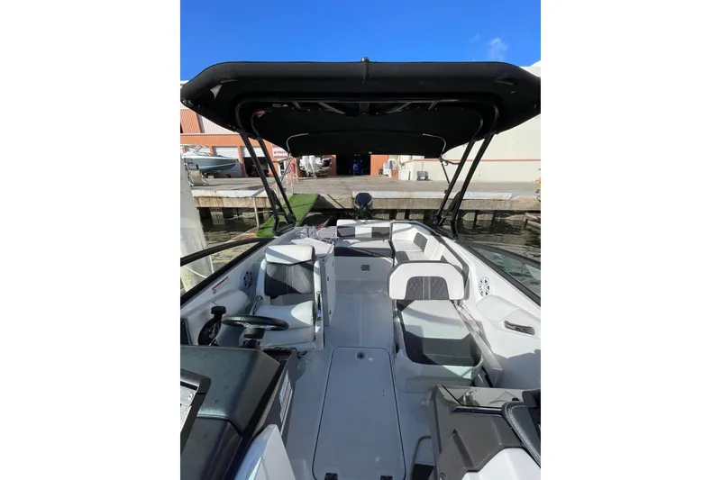 Slide: The Image of 2022 Monterey M-65 boat interior with seating and canopy, docked under clear blue sky. - 5