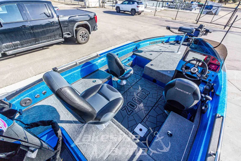 Slide: The Image of 2024 Recon 985 SC boat interior with seating and steering, parked near vehicles. - 14