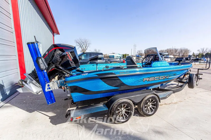 Slide: The Image of 2024 Recon 985 SC boat in vibrant blue, parked outdoors on a trailer. - 3
