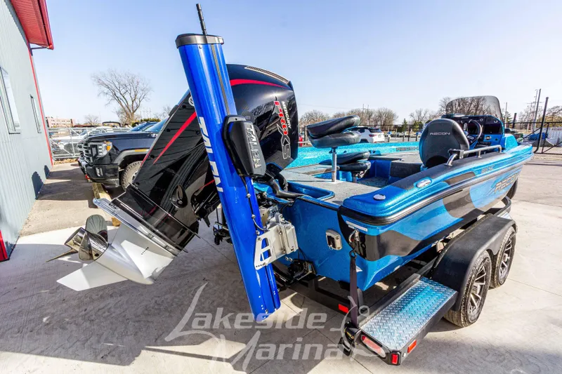 Slide: The Image of 2024 Recon 985 SC boat in blue, parked at Lakeside Marina with powerful outboard motor. - 4