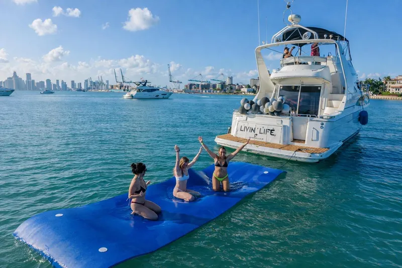 The Image of 2004 Carver 420 Mariner yacht with people enjoying a floating mat in sunny waters. - 1