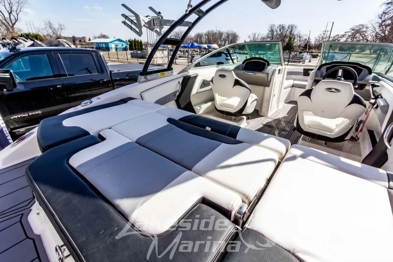 Slide: The Image of 2023 Chaparral 21 Surf boat interior with seating and steering wheel, displayed at marina. - 13