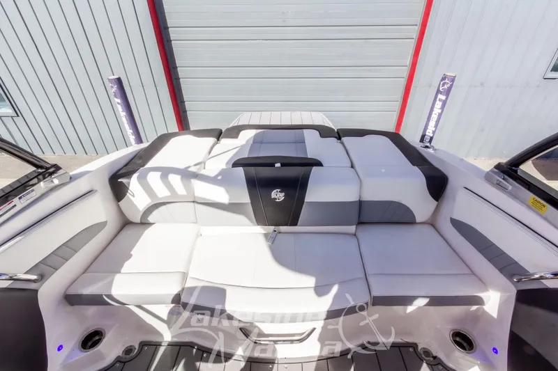 Slide: The Image of 2023 Chaparral 21 Surf boat interior with white and gray seating, docked outdoors. - 17
