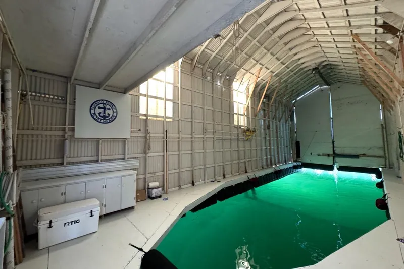 The Image of Custom 2000 boathouse interior with green water, storage cabinets, and nautical decor. - 0