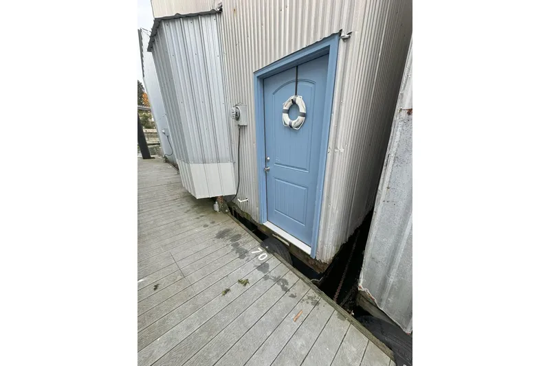 Slide: The Image of Blue door with lifebuoy on custom boathouse, wooden dock, overcast day. - 3
