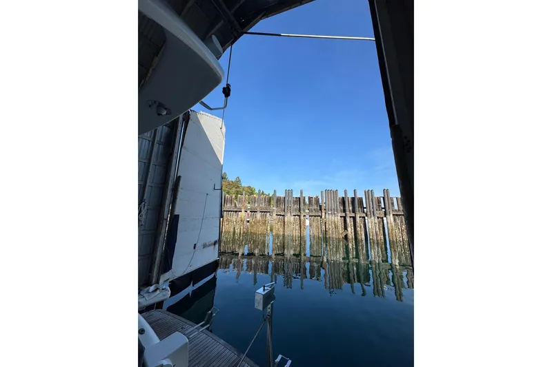 Slide: The Image of Custom 2000 boathouse interior view with open door, overlooking calm water and wooden pilings. - 4