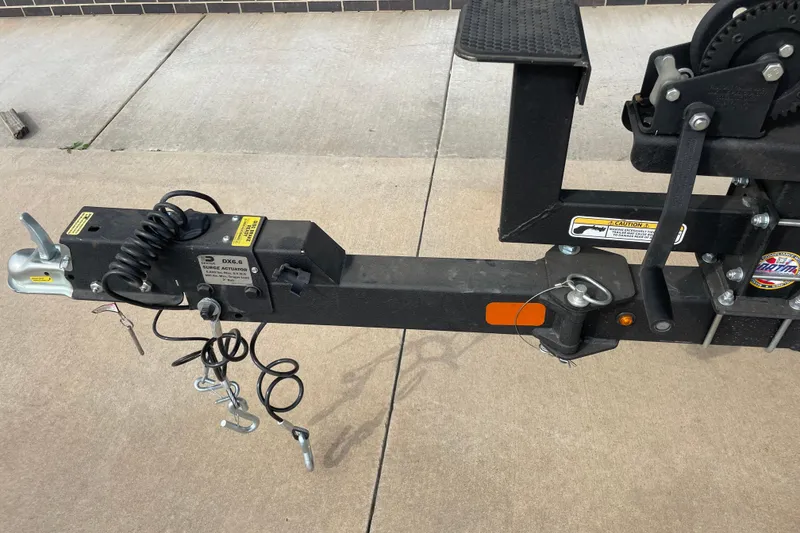 Slide: The Image of Trailer hitch of 2026 Tracker Pro Team 195 boat, featuring surge actuator and safety chains. - 9