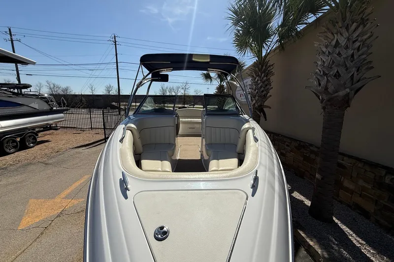 Slide: The Image of 2009 Cobalt 242 boat with white interior, parked outdoors under a clear sky. - 3