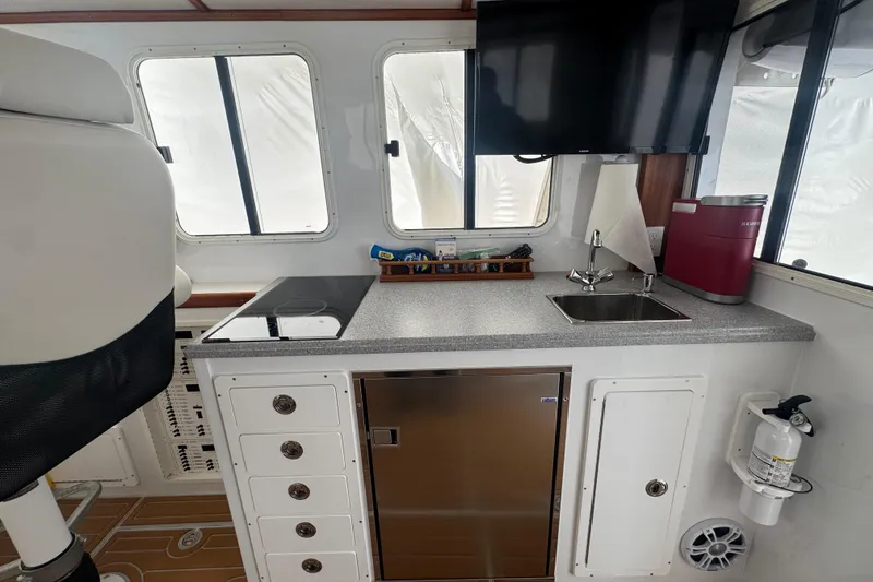 Slide: The Image of Interior of 2000 Northern Bay 38, featuring kitchenette with sink, stove, and storage. - 12