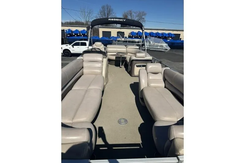 Slide: The Image of 2015 Regency 220 DL3 pontoon boat with beige seating and canopy, docked outdoors. - 12