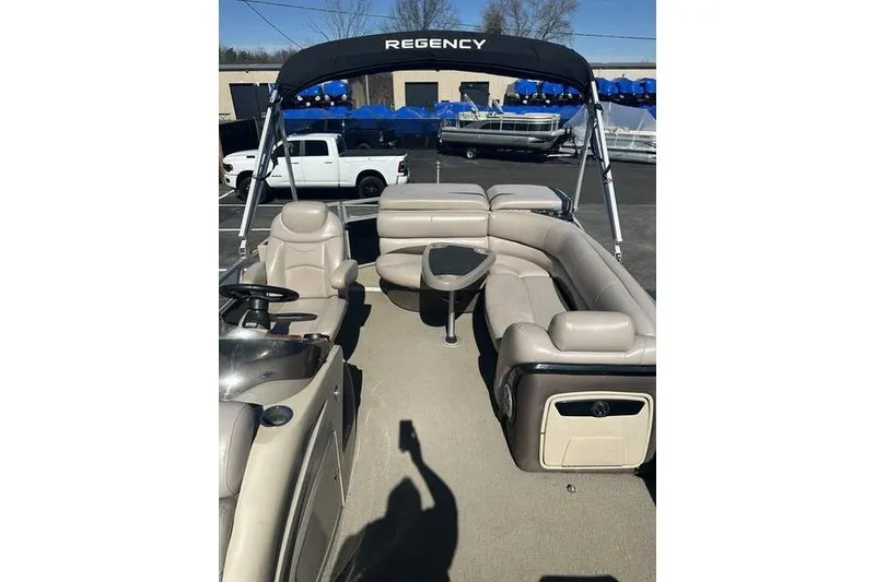 Slide: The Image of 2015 Regency 220 DL3 pontoon boat with beige seating and canopy in a parking lot. - 8