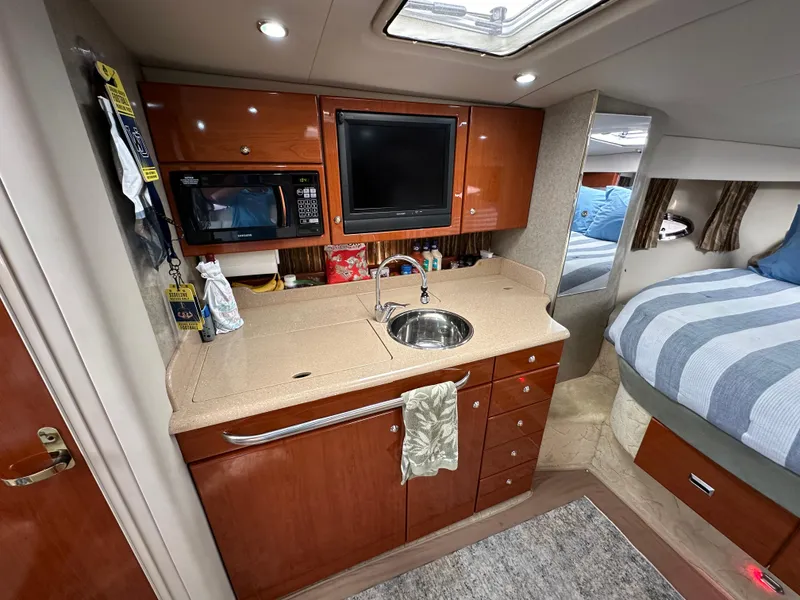 Slide: The Image of 2004 Formula 34 PC yacht interior with kitchenette, microwave, sink, and cozy sleeping area. - 18