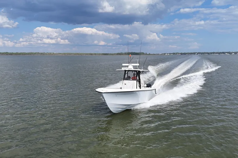 Slide: The Image of 2023 SeaVee 32 boat cruising on open water under a partly cloudy sky. - 45