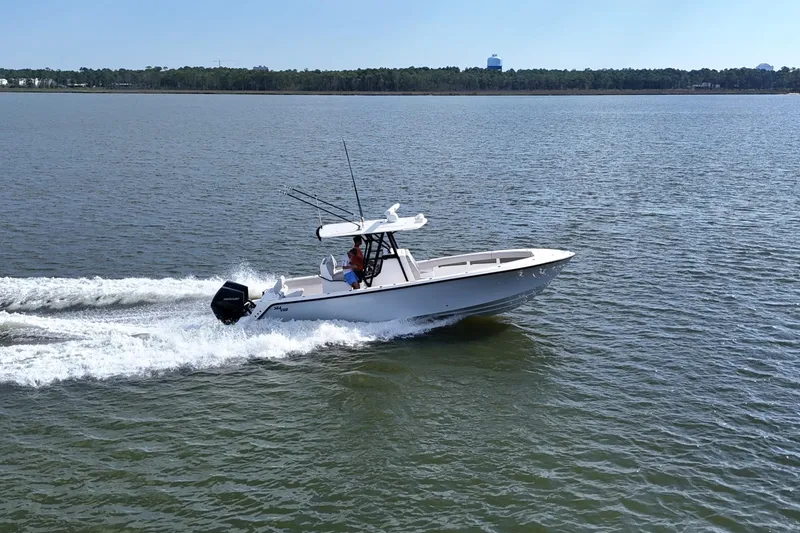 Slide: The Image of 2023 SeaVee 32 boat cruising on a calm lake with a forested shoreline. - 50