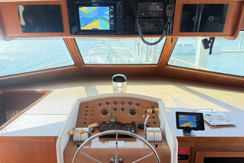 Slide: The Image of 1987 Hatteras 54 Motor Yacht helm with navigation screens and controls, overlooking marina. - 33