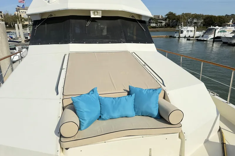 Slide: The Image of 1987 Hatteras 54 Motor Yacht with cushioned deck seating and blue pillows at marina. - 38