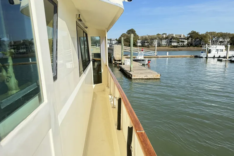 Slide: The Image of 1987 Hatteras 54 Motor Yacht docked at a marina, calm waters, clear sky. - 39