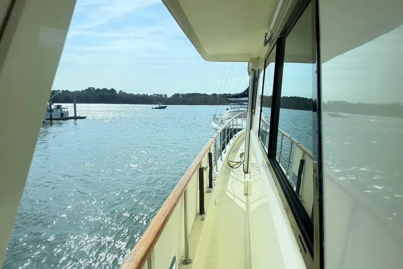 Slide: The Image of 1987 Hatteras 54 Motor Yacht cruising on a sunny day, reflecting on calm waters. - 43