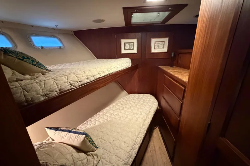 Slide: The Image of Cozy cabin with bunk beds in 1987 Hatteras 54 Motor Yacht, featuring wood paneling and porthole windows. - 55