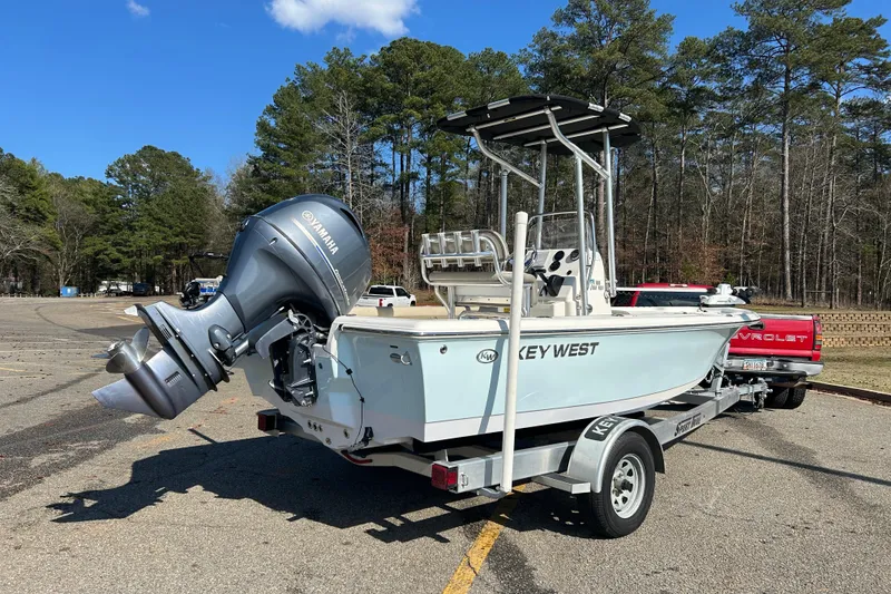Slide: The Image of 2021 Key West 188 Bay Reef boat with outboard motor, parked near a scenic lake. - 3