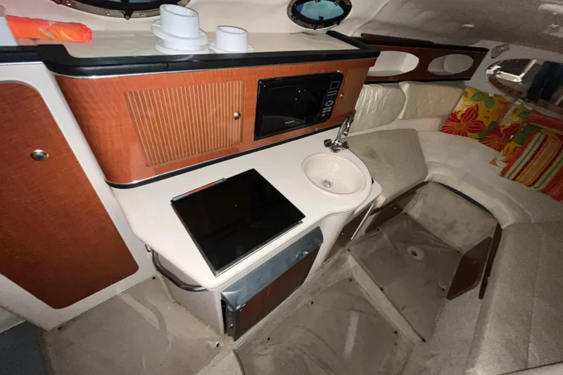 Slide: The Image of 2004 Sea Ray Sundancer 260 cabin interior with kitchenette, sink, and seating area. - 11