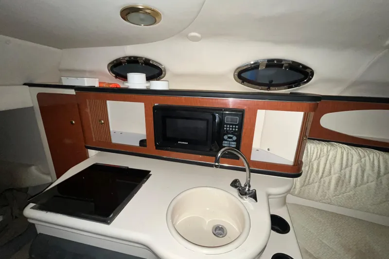 Slide: The Image of 2004 Sea Ray Sundancer 260 cabin kitchen with microwave, sink, and storage. - 15