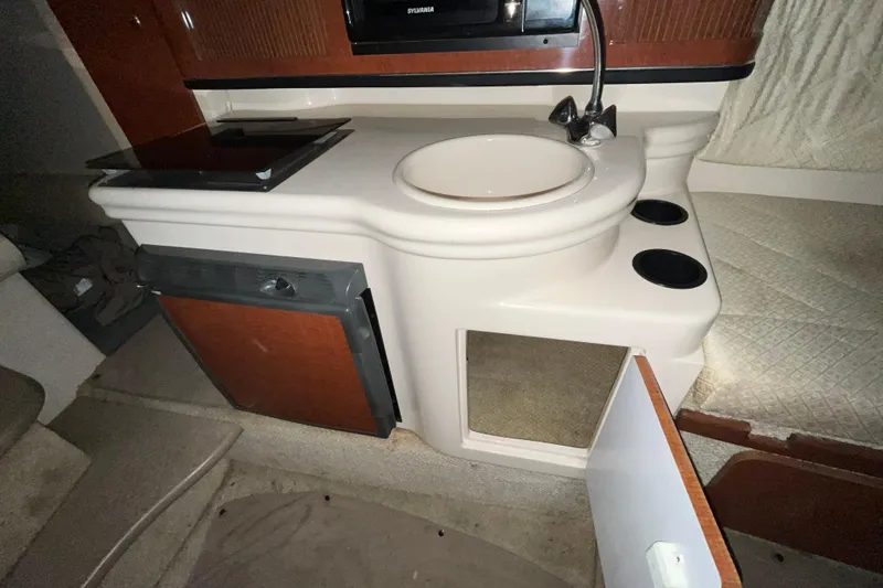 Slide: The Image of 2004 Sea Ray Sundancer 260 interior with sink, stove, and open cabinet. - 25