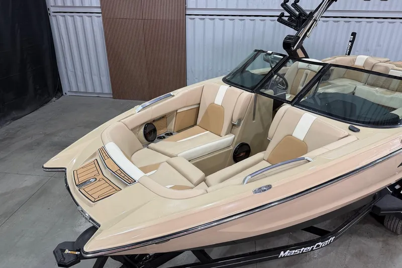 Slide: The Image of 2025 MasterCraft X24 boat interior with beige and white seating, displayed indoors. - 15