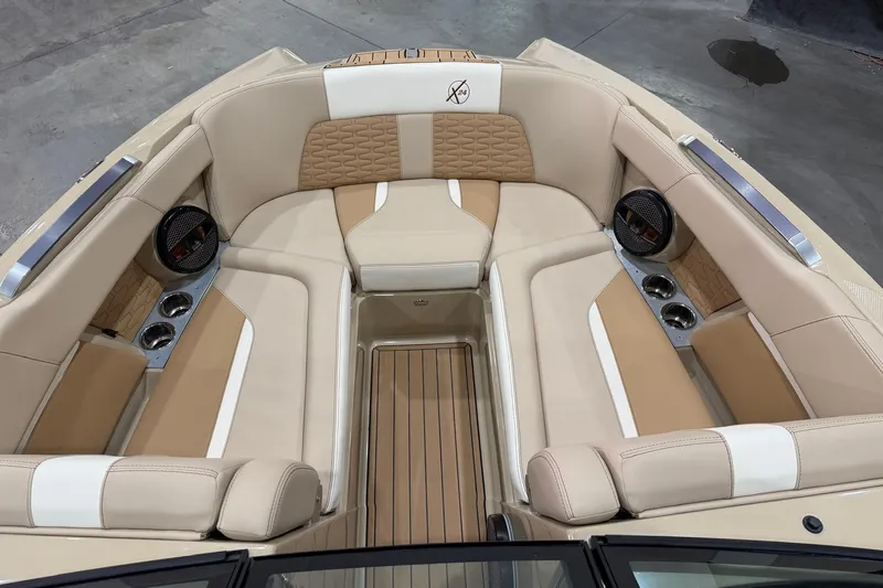 Slide: The Image of 2025 MasterCraft X24 boat interior with beige and white seating, cup holders, and speakers. - 23