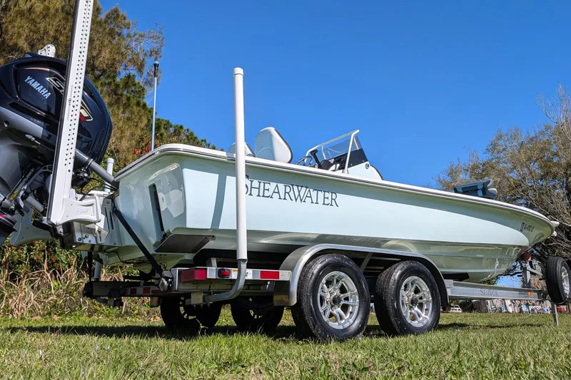 Slide: The Image of 2023 ShearWater X22 Hybrid boat on trailer with Yamaha engine, parked on grass. - 10