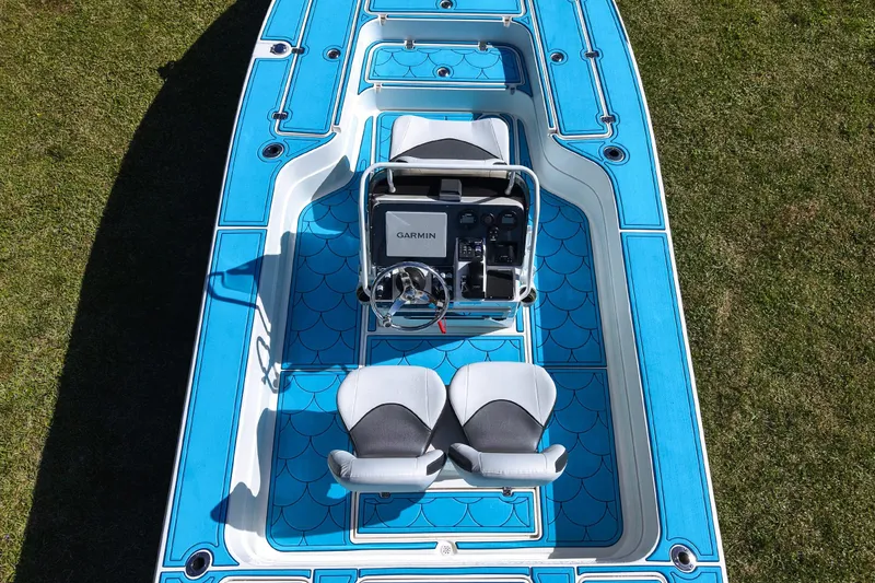 Slide: The Image of 2023 ShearWater X22 Hybrid boat with blue deck and dual seats on grass. - 30
