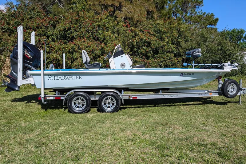 Slide: The Image of 2023 ShearWater X22 Hybrid boat on trailer, parked on grass. - 4