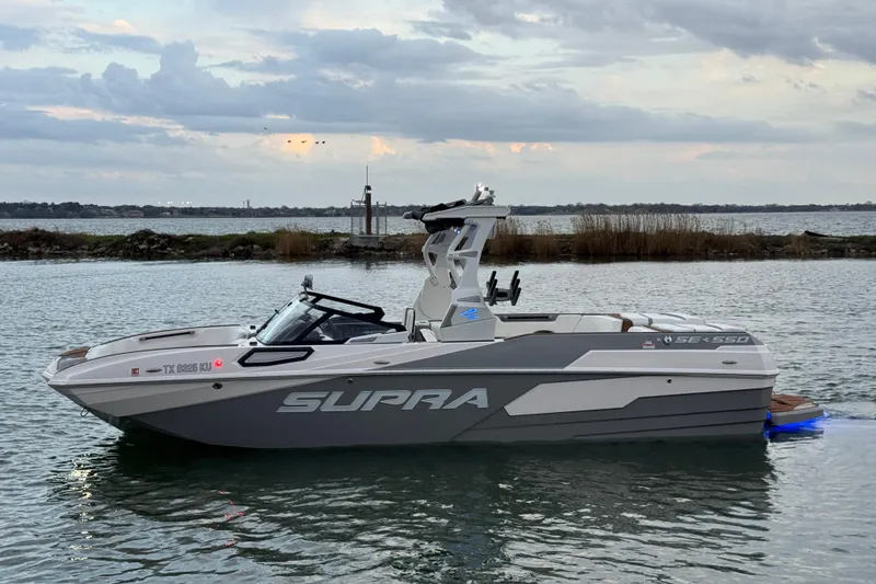 The Image of 2023 Supra SE 550 boat on calm water under cloudy sky. - 1