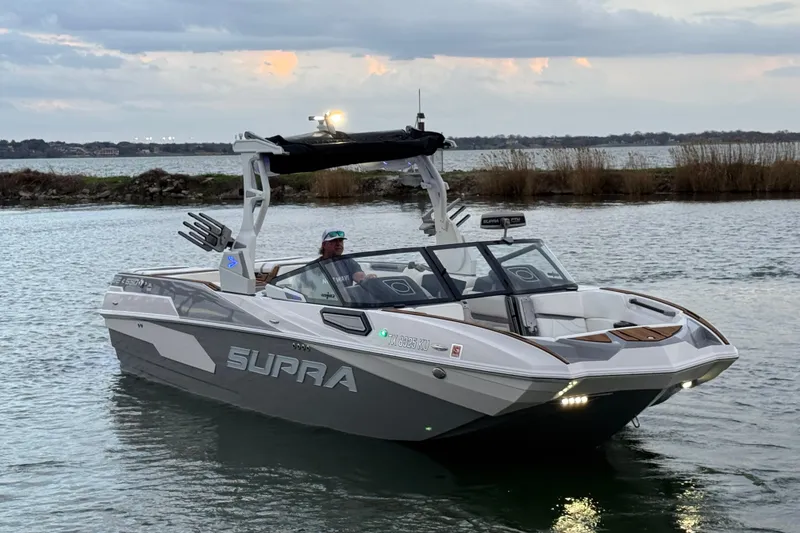 Slide: The Image of 2023 Supra SE 550 boat cruising on a calm lake at sunset. - 4