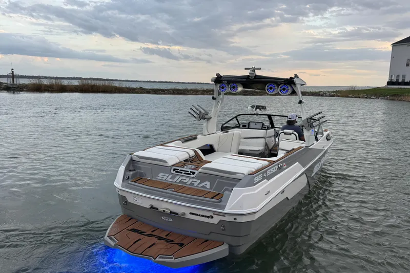 Slide: The Image of 2023 Supra SE 550 boat on water with illuminated deck and scenic background. - 6