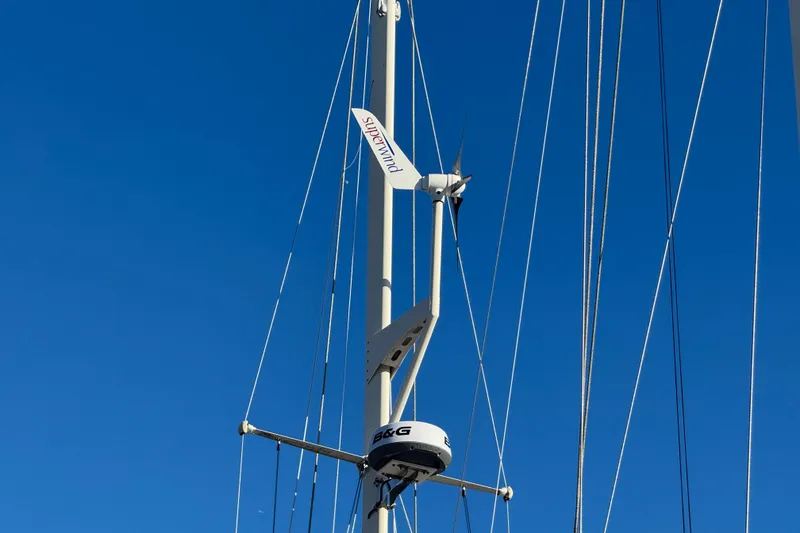 Slide: The Image of Mast of 1988 Amel Sharki sailboat with Superwind turbine against clear blue sky. - 2