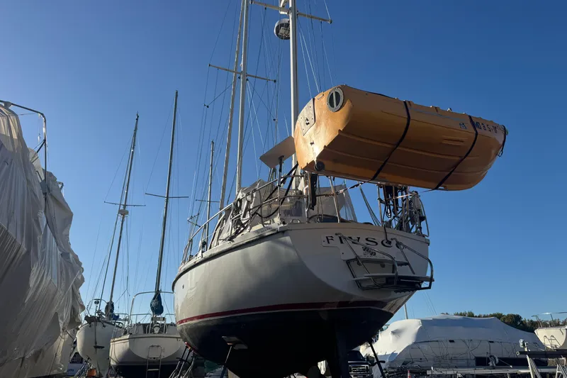 Slide: The Image of 1988 Amel Sharki sailboat in dry dock with lifeboat, clear blue sky background. - 5